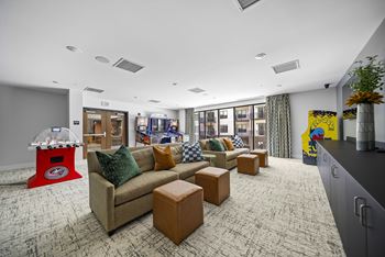 A room with a couch, a coffee table, and a gaming machine.